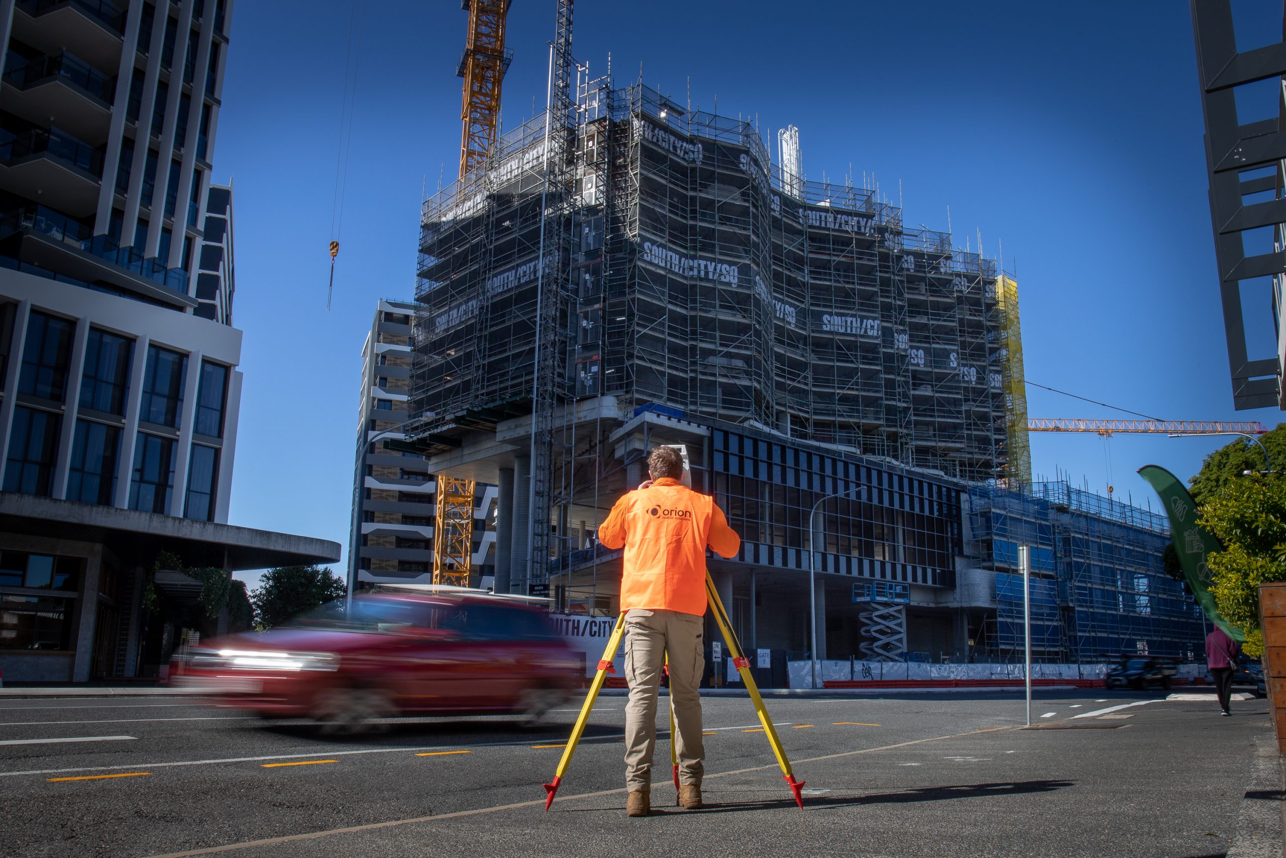 Lifestyle image of a surveyor using equipment with half built apartment block in the background